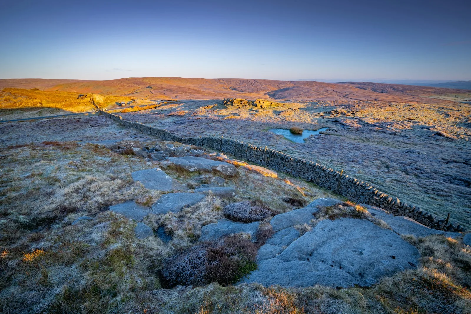 A dry-stone wall crossing frosted moorland near Clapham at sunrise