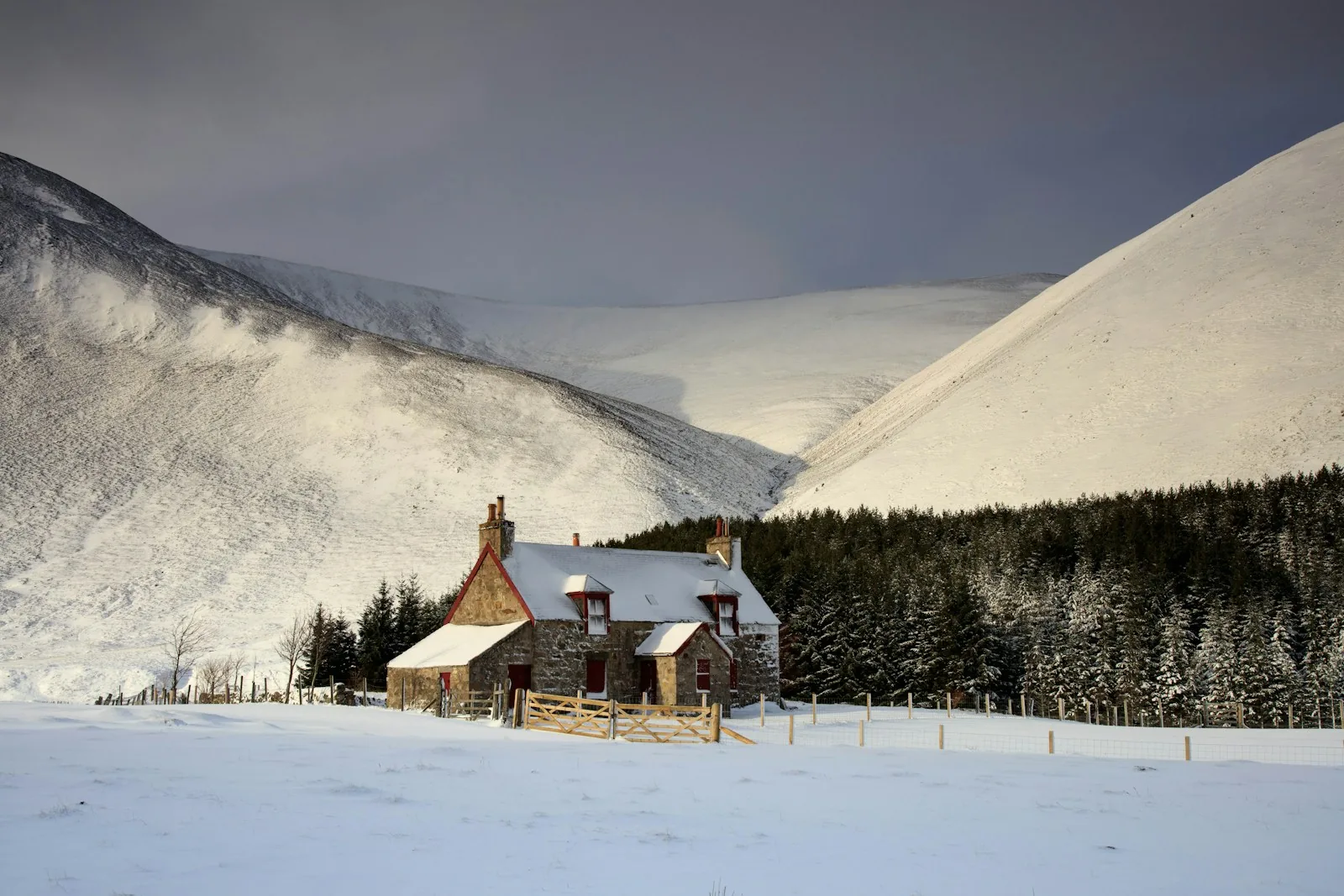 A stone cottage surrounded by snow-covered hills near Braemar, Scotland